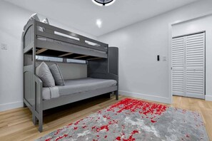 A bunk bed with grey bedding and pillows, a red and grey patterned rug, and a white door with horizontal blinds. - Modern and Spacious 3BR - 2BA Miami - Free Parking (Miami)