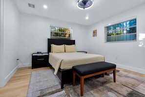 A bedroom with a bed, bedside table, bench, and a window with a view. - Serenity Grove 3BR|2BA - Free Parking - Tropical (Miami)