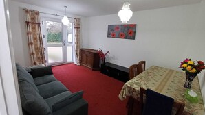 Un salon comprenant un canapé, une table à manger avec des chaises, un lustre et un tableau accroché au mur.