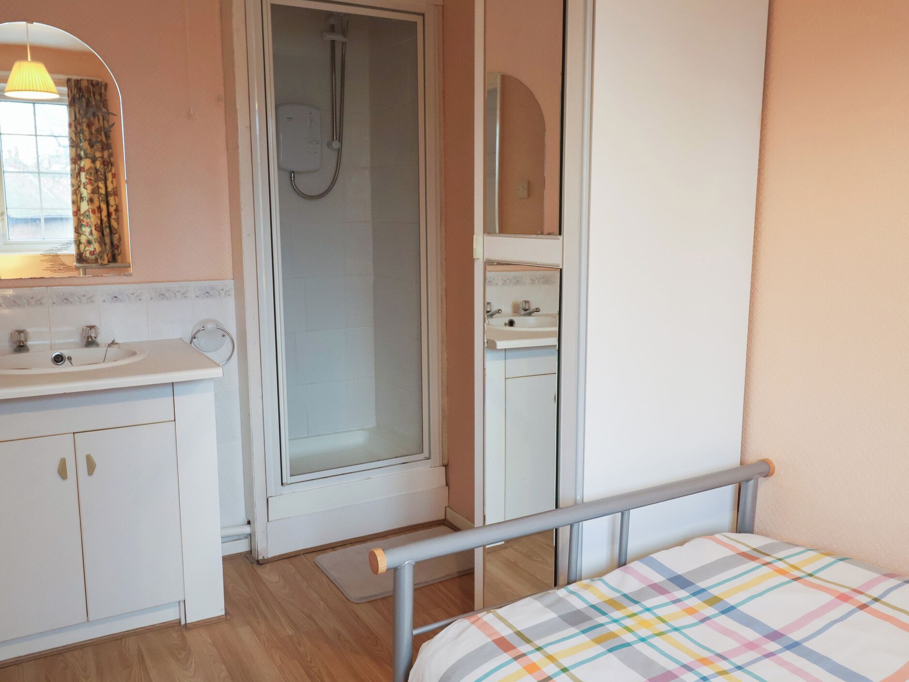 A bedroom with a bed, a bathroom with a shower, and a sink.