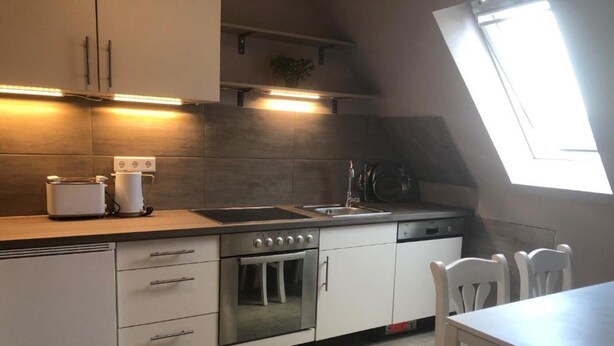 A kitchen with white cabinets, a built-in oven, a microwave, and a toaster. There is a skylight above the sink. - Apartment "Wohnung mit Fernblick" with Private Garden and Wi-Fi (Jübek)