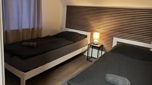 A room with a bed, a bedside table with a lamp, and a slatted headboard. - Apartment "Wohnung mit Fernblick" with Private Garden and Wi-Fi (Jübek)