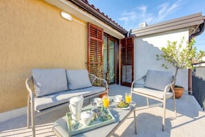 A patio with two white cushioned chairs, a tray with breakfast items, and a potted plant. - Vila Leonarda (Miren-Kostanjevica)