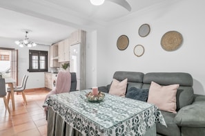 Una sala de estar con sofá, una mesa de comedor y una cocina al fondo.