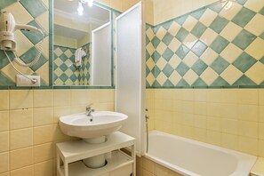 Une salle de bain équipée d’un lavabo, d’un miroir et d’un sèche-cheveux fixé au mur.