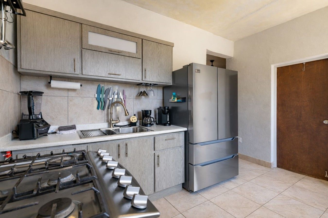 Una cocina moderna con estufa a gas, electrodomésticos de acero inoxidable y armarios grises claros.