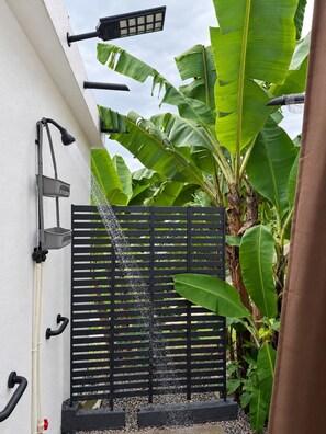 A black metal fence with water cascading down, a wall-mounted light fixture, and a black pipe. - Private 7-Acre El Yunque Retreat | Generator (luquillo)