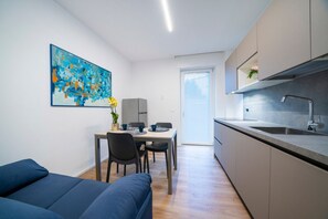 A modern kitchen with a dining area, a sofa, and a painting on the wall.