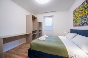 A bedroom with a bed, a wardrobe, a window, and a painting.