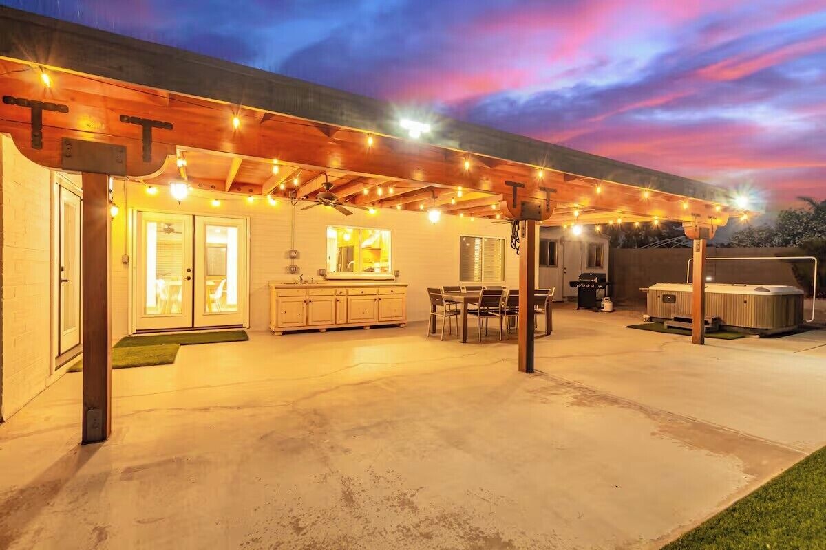 A covered patio area with string lights, a wooden ceiling, and a concrete floor.