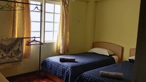 A small, compact room with two beds, a window with curtains, and a wall-mounted drying rack. - Bderiah Cameron Guest House +Wi-Fi-Netflix-Garden view (Tanah Rata)