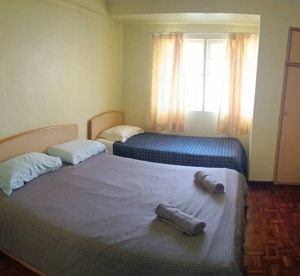 Ein Zimmer mit zwei Betten, einem Vorhangfenster und Holzboden.