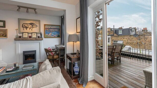 Una sala de estar acogedora con chimenea, comedor y balcón con vistas a la ciudad.