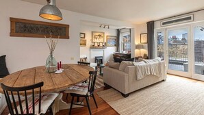 Una sala de estar acogedora con chimenea, un comedor con mesa y sillas de madera, y un balcón con vistas.