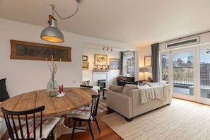 Ein gemütliches Wohnzimmer mit Kamin, ein Essbereich mit Holztisch und Stühlen sowie ein Balkon mit Aussicht.