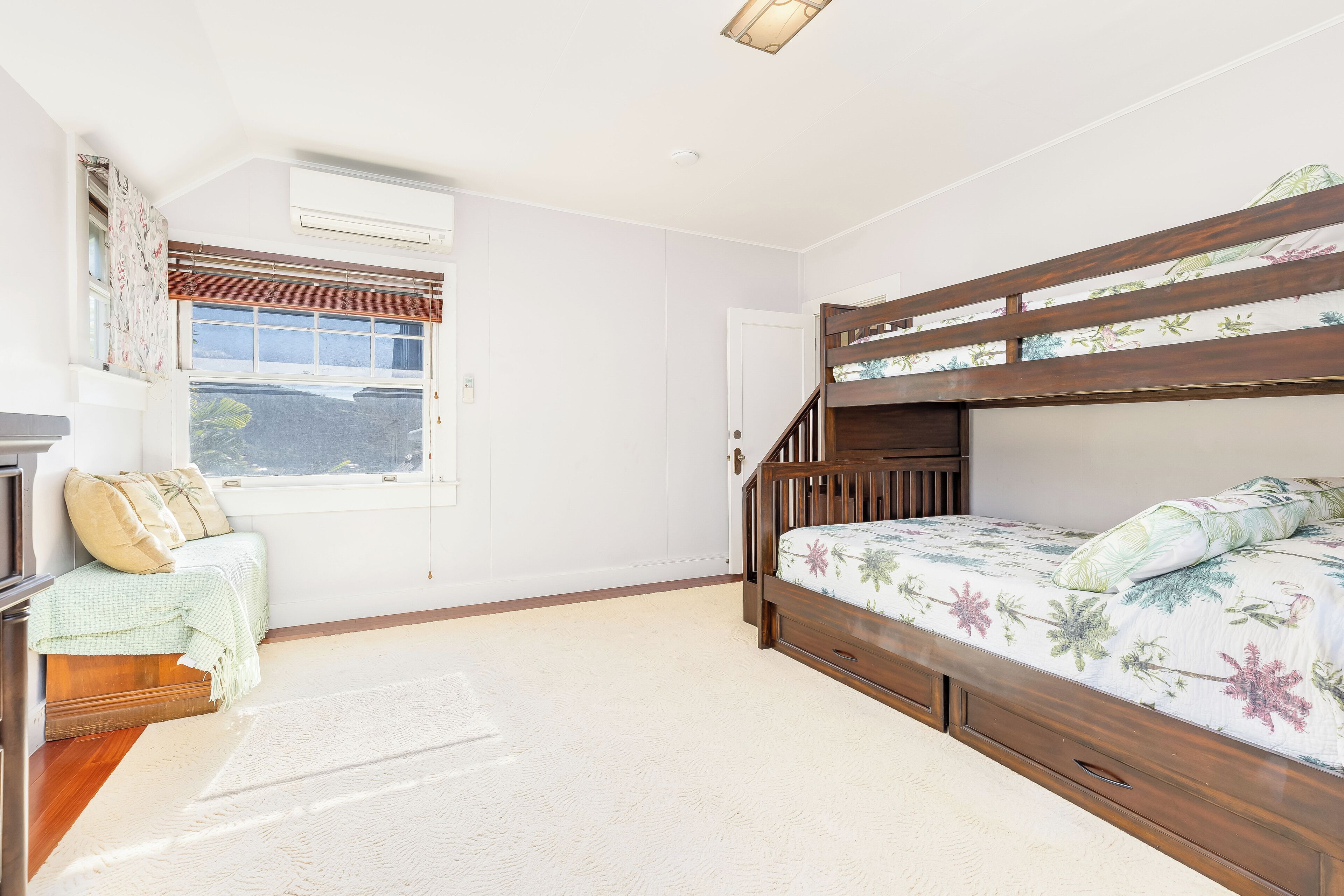 Une chambre avec un lit superposé, un bureau avec une chaise, une fenêtre avec des stores et une porte.