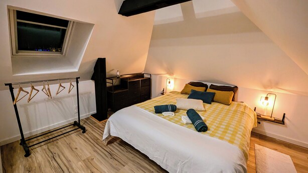 Un dormitorio con cama, escritorio, silla, televisor y ventana.