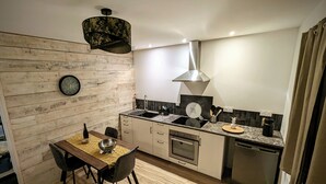 Una cocina compacta con una pared de madera, una mesa de comedor con sillas, un fregadero, una estufa y un lavavajillas.