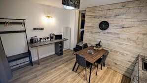 Una cocina compacta con comedor, una cafetera y un reloj en la pared.