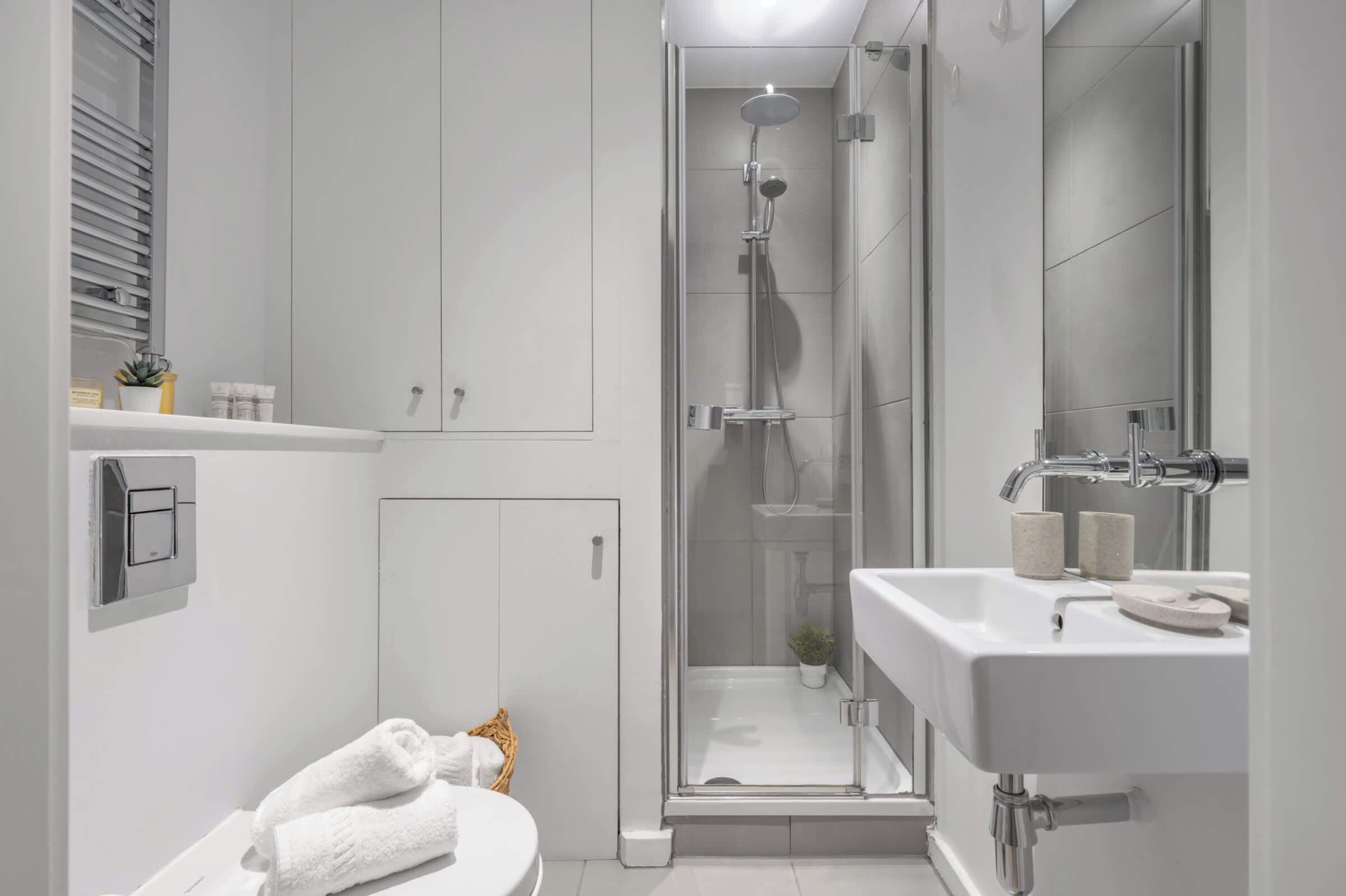 Un baño moderno con ducha acristalada, lavabo blanco y retrete.