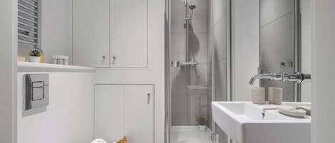 Un baño moderno con ducha acristalada, lavabo blanco y retrete.