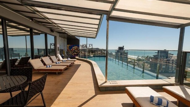 Un espace piscine aménagé sur le toit, avec des chaises longues et une vue sur la ville.
