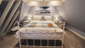 Una camera da letto con un letto, due comodini, un quadro appeso al muro e una scala a sinistra.