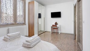 Een hotelkamer met een bed, een stoel, een televisie en een kledingkast.