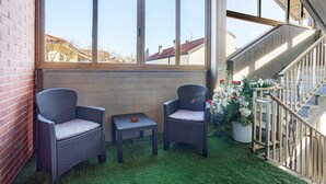 Un balcon avec deux fauteuils en osier, une petite table et une plante en pot.