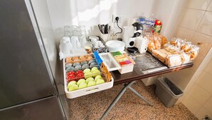 Une petite cuisine équipée d’une machine à café, d’une bouilloire, d’un grille-pain et d’un assortiment de produits alimentaires, notamment du pain et des viennoiseries.