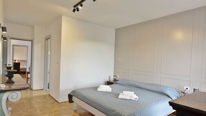 Une chambre à coucher avec un lit, des tables de chevet, un bureau et un miroir.