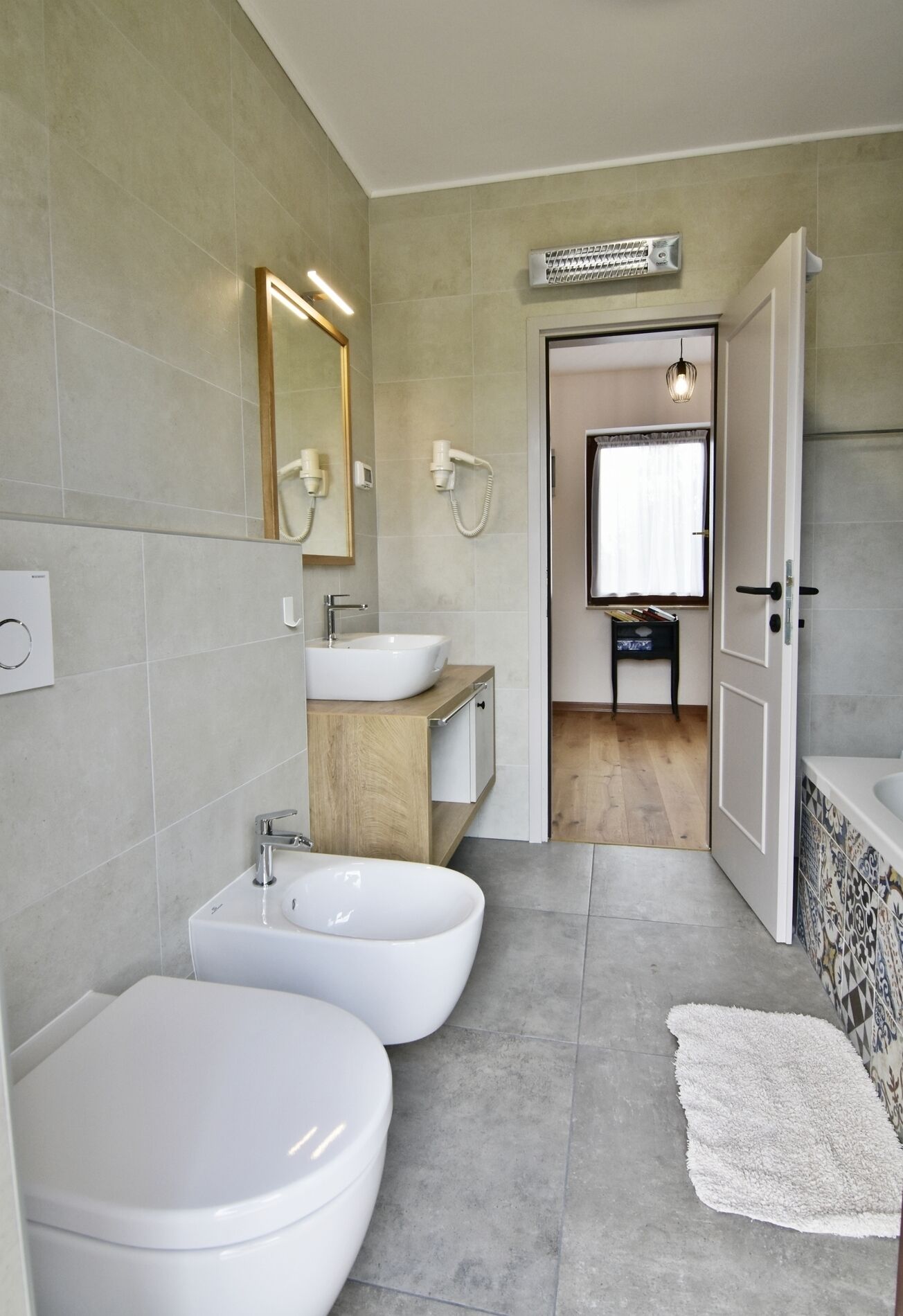 A modern bathroom with two sinks, a large mirror, and a walk-in shower.
