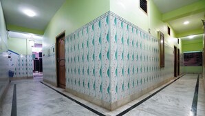 Ein Korridor mit Wandverkleidung und Marmorboden, der zu mehreren Türen führt.