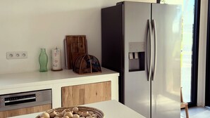 Ett modernt kök med ett kylskåp i rostfritt stål, en vit bänkskiva och en korg med keramikföremål.