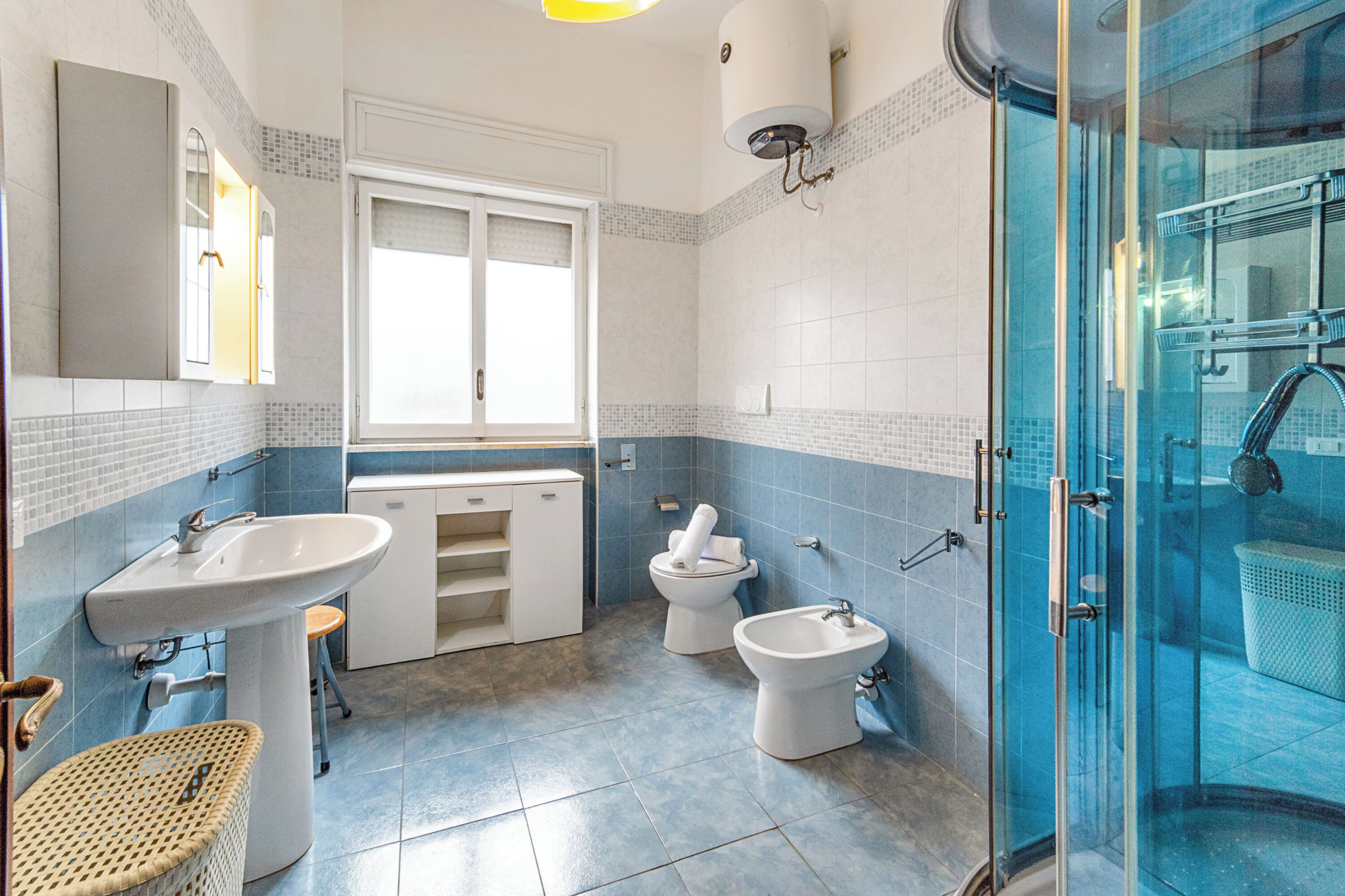 A bathroom with two sinks, a toilet, a shower, and a window.