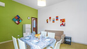Un comedor con una mesa dispuesta para cuatro personas, un refrigerador y un sofá.