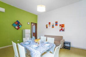A dining area with a table set for four, a refrigerator, and a sofa. - Sunny Sea View (Melendugno)