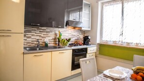 Una cocina moderna con estufa a gas, cafetera y comedor con mesa para dos.