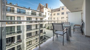 En balkon med gelænder af glas, et bord og to stole.