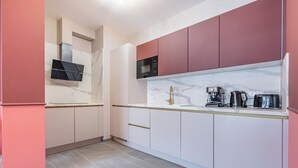 Et moderne køkken med hvide og røde skabe, en marmorbordplade og en indbygget mikrobølgeovn.