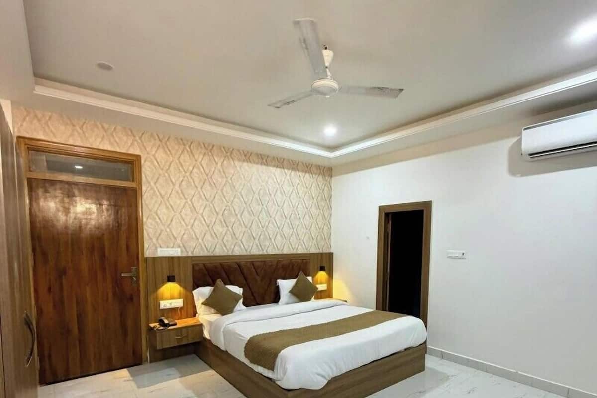 Une chambre à coucher comprenant un lit, des tables de chevet, un ventilateur de plafond et un appareil de climatisation.