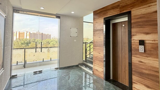 Un interior moderno con piso de mármol pulido, un muro decorativo de madera y vistas a edificios a través de un ventanal amplio.