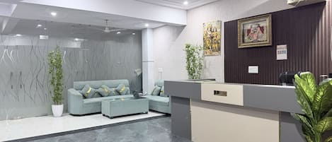 A modern reception area with a sofa, reception desk, and decorative plants.