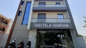 Un edificio de varios pisos con un letrero que dice 'SHRI PREM SHARNAM' en la entrada.
