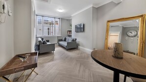 Un salon moderne avec un canapé gris, une table à manger en bois et un grand miroir.