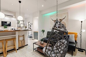 A modern living space with a kitchen, dining area, and a hanging chair. - 1AS 5★ LUXURY FARM STAY BARNDOMINIUM - CEDAR POND FARMS - SCOTTISH HIGHLAND... (Jefferson City)