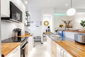 Une cuisine moderne dotée d’un îlot central, d’appareils électroménagers intégrés et d’un luminaire suspendu.