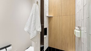Un baño con tocador de madera, una toalla colgada en la pared y artículos de aseo en la encimera.