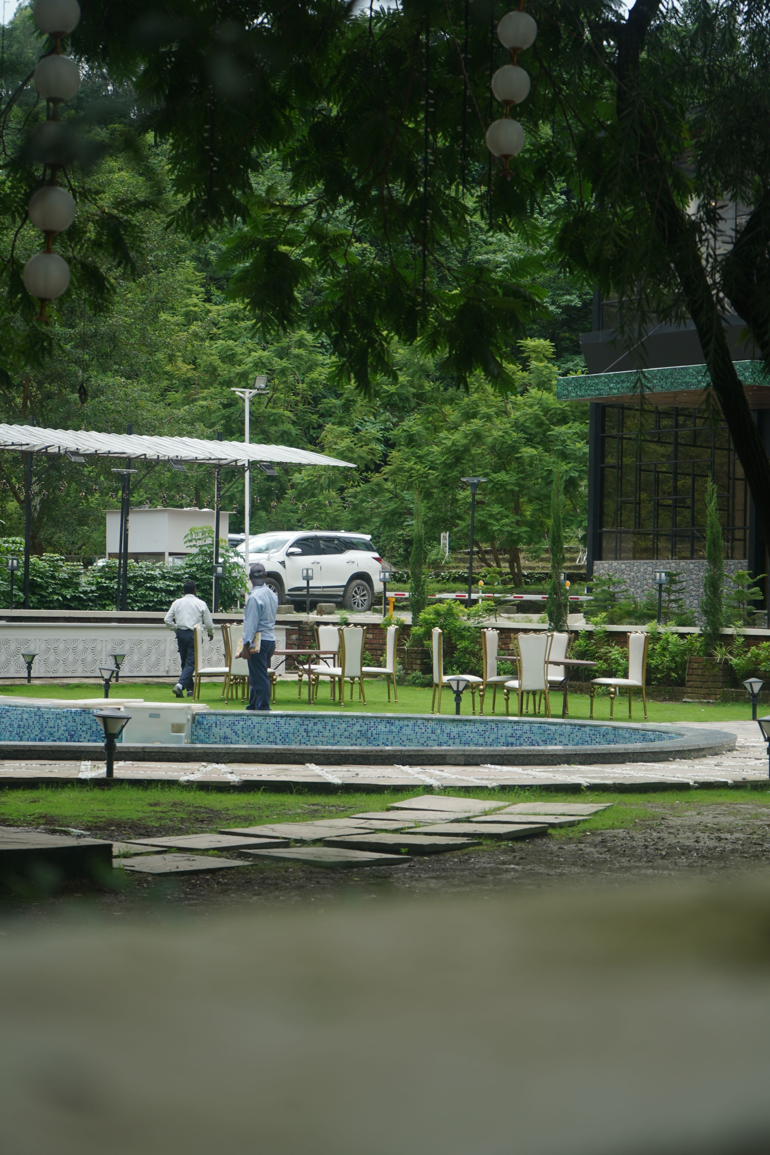 A parking area with a white car, outdoor seating, and a fountain.