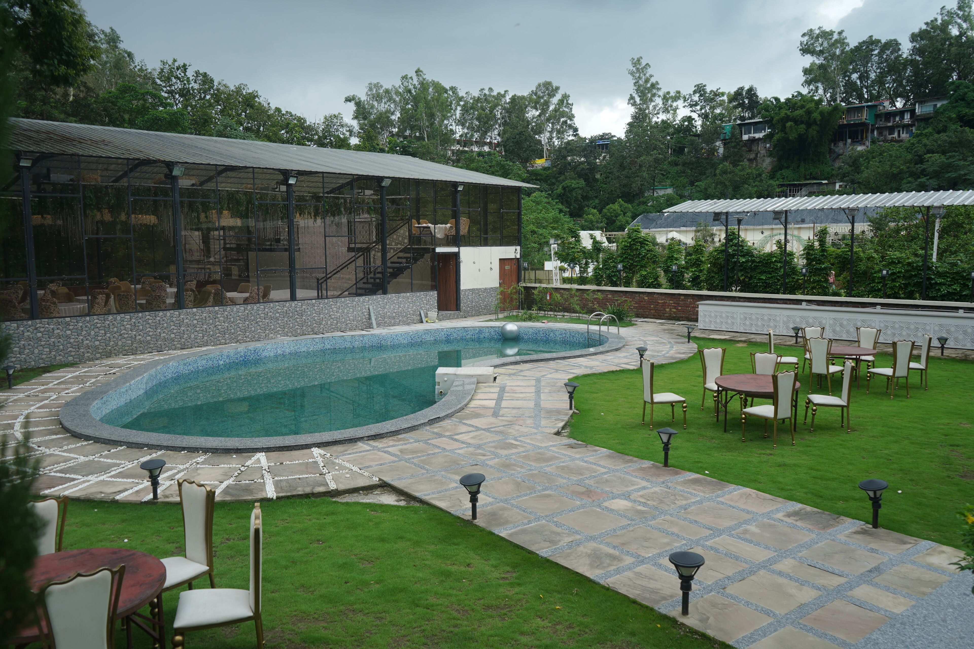 Un espace piscine doté d’une terrasse en pierre, de chaises longues et d’un coin salon abrité.